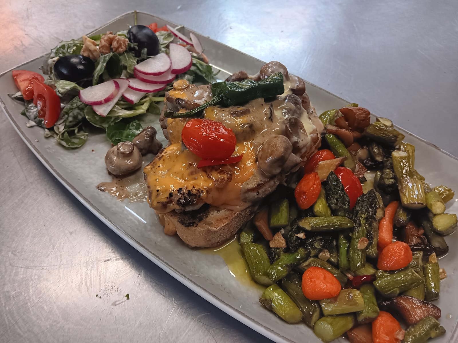 Herzhaft belegtes Brot mit geschmolzenem Käse und Pilzen, dazu bunte Beilagen